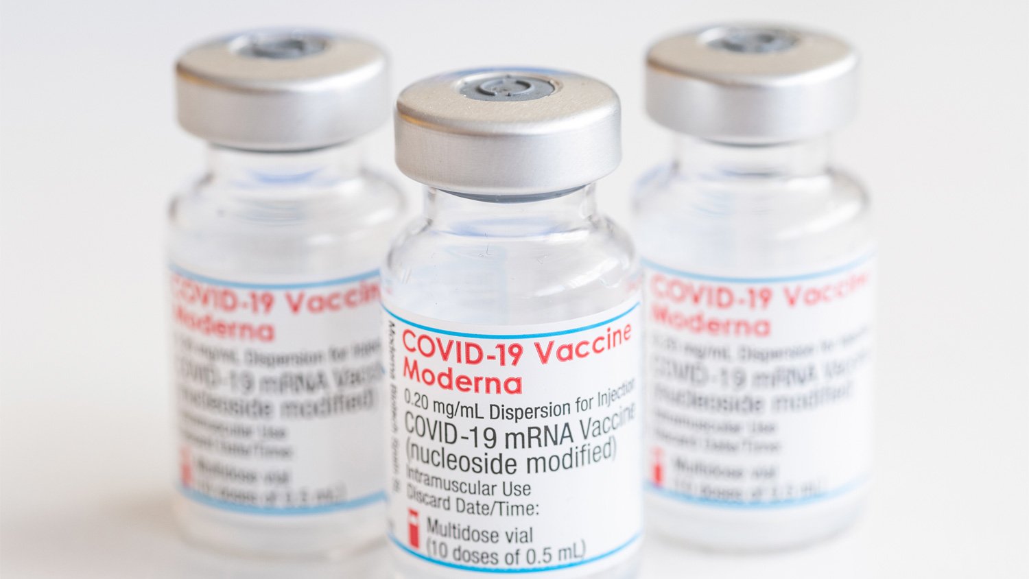 Three glass vaccine vials labelled COVID-19 Vaccine Moderna.