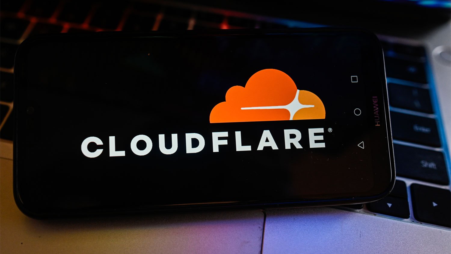 CloudFlare logo is displayed on a smartphone with stock market percentages on the background.