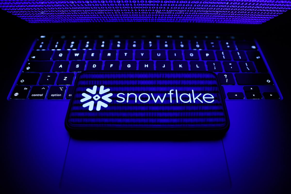 A phone showing the Snowflake logo. Phone laying on top of a laptop keyboard. 