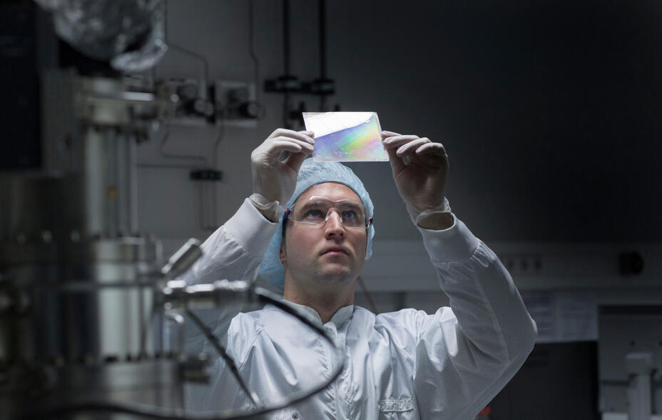 Technician in cleanroom examining sample.