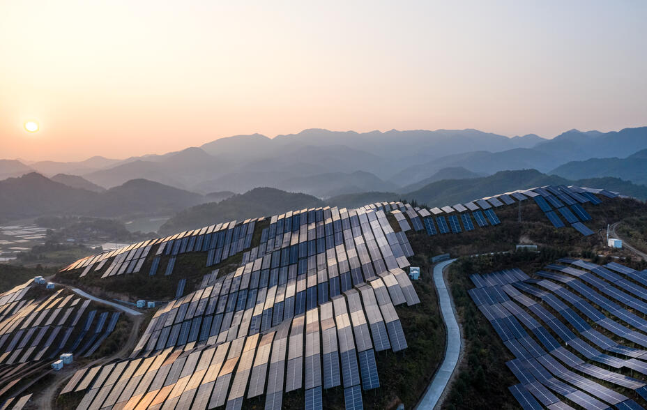 Aerial view of a Chinese solar power plant on a mountaintop at sunset.
