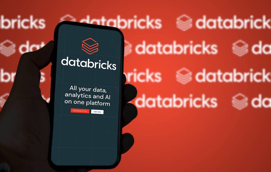 A hand holding a phone with the Databricks logo, with a red background with white Databricks logos