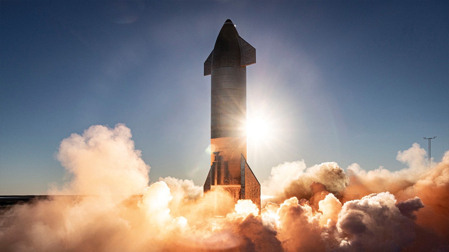 Space X Starship launching through a plume of exhaust smoke.