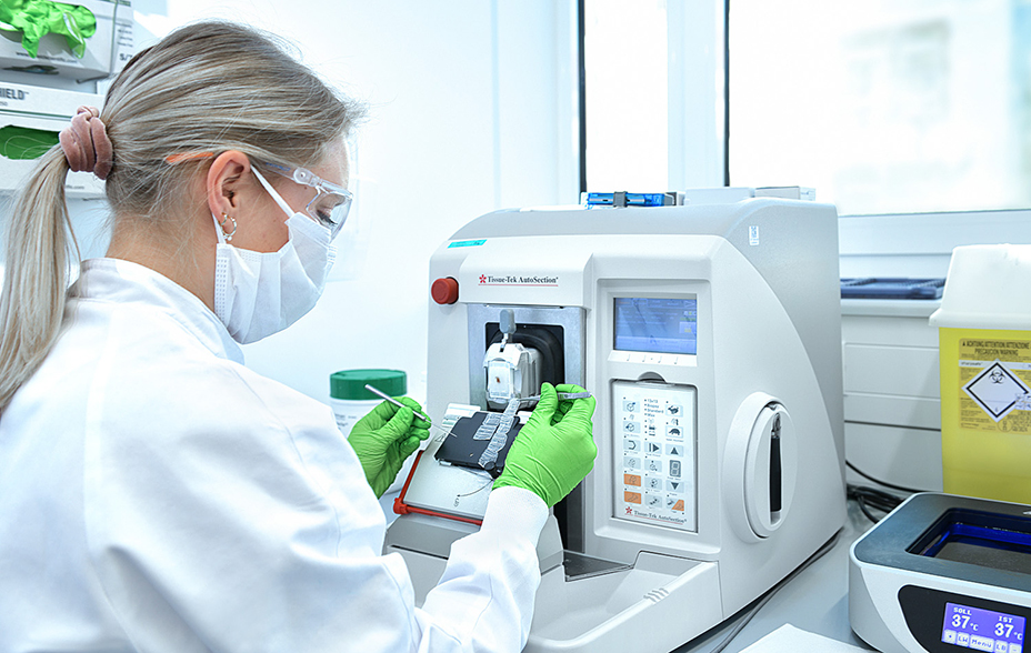Laboratory technician in mask and goggles loads samples into an automated analysis machine.