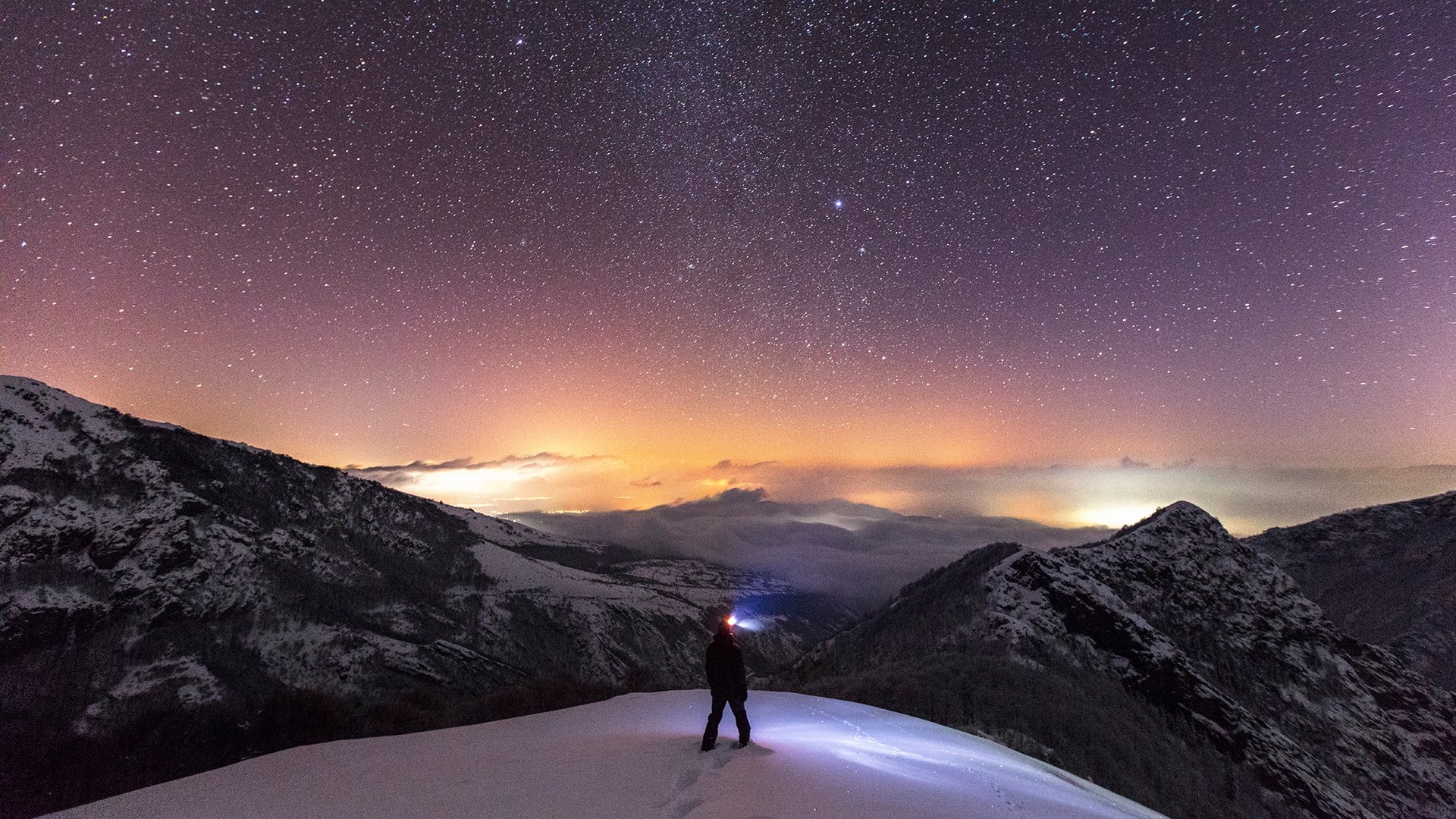 Person on mountain summit with night sky