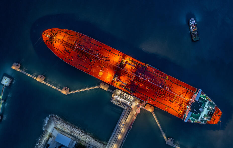 An oil tanker is docked in a harbour, viewed from above at night.